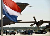 Dutch flag with an airplane, people with cars in the background.