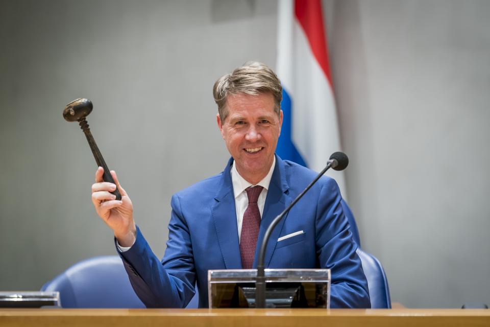 Chairman Martin Bosma is seated at the Chairman's seat in front of the Dutch flag. In his right hand is is holding the chairman's hammer.
