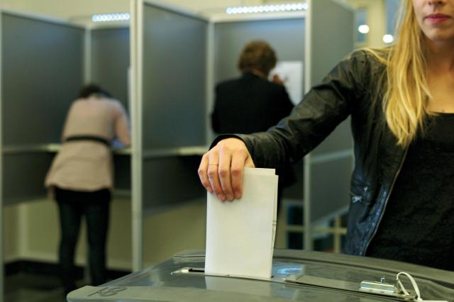 A woman puts her vote into the election collection bin