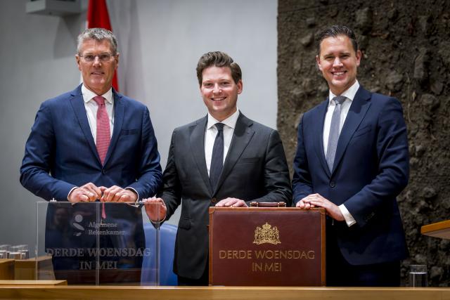 The president of the Netherlands Court of Audit, Pieter Duisenberg (left), President of the House of Representatives Thom van Campen and Minister of Finance Eelco Heinen stand behind a table and hold two attache cases. 