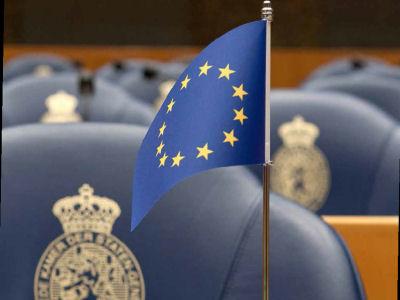 Blue chairs in the plenary Hall with a European flag